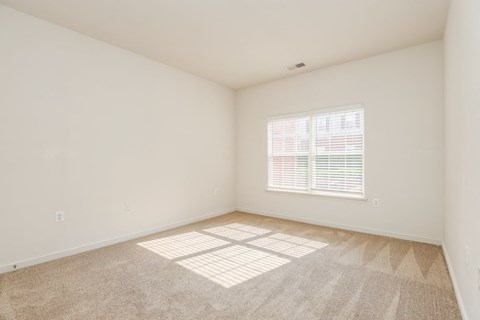 a bedroom with a window and carpeted floor