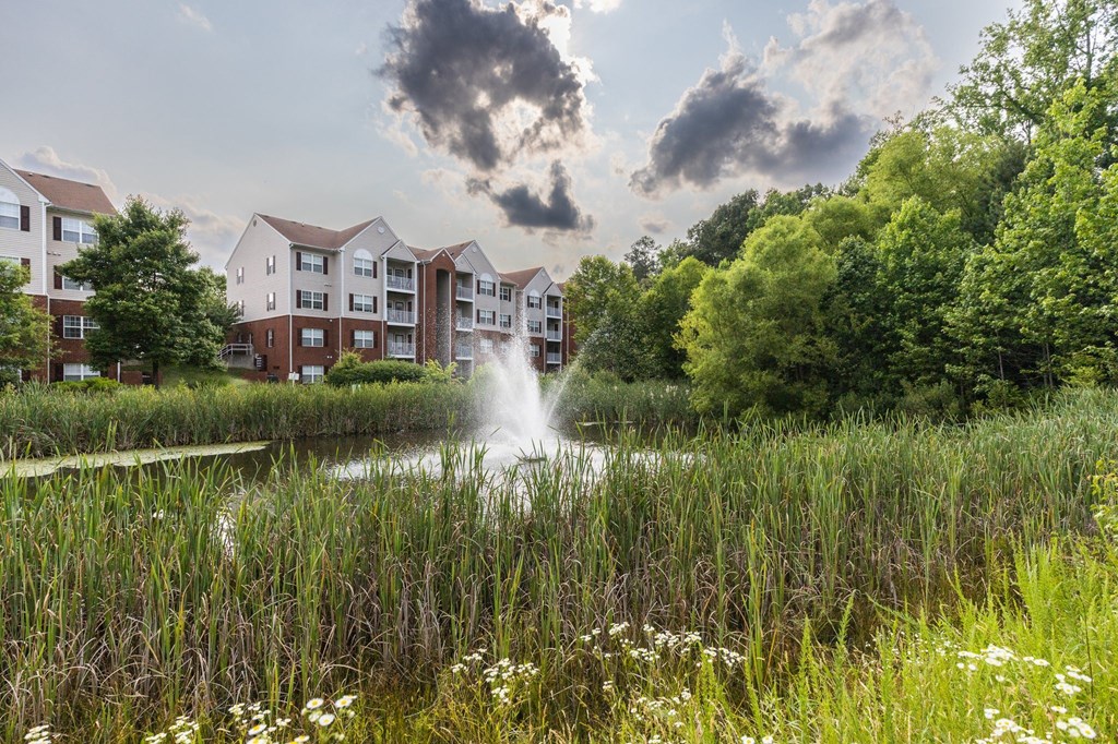 a fountain in a pond in front of an apartment building