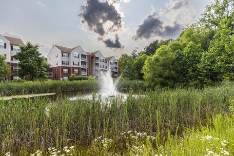 a fountain in a pond in front of an apartment building