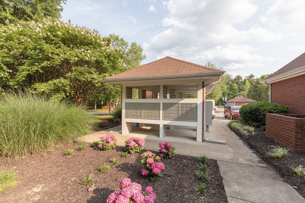 a white gazebo with a porch and pink flowers