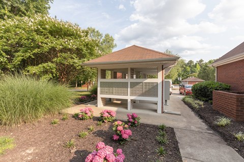 a white gazebo with a porch and pink flowers
