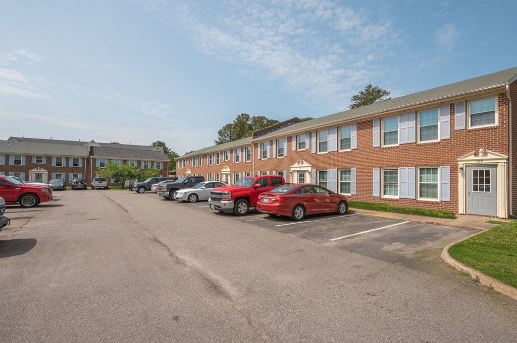 a parking lot with cars in front of a brick apartment building