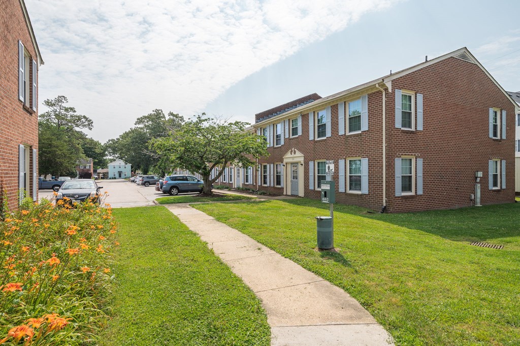 a sidewalk in front of a brick apartment building