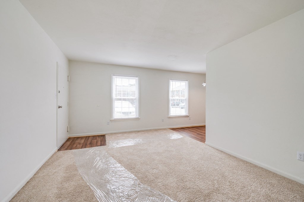 a living room with a carpeted floor and two windows