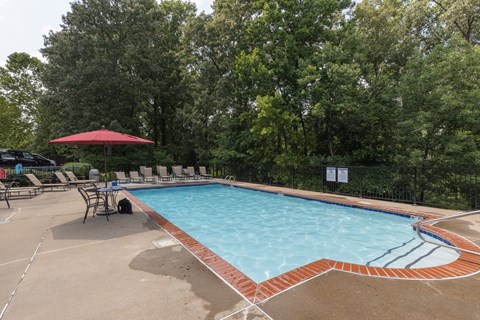 a swimming pool with chairs and a table and a umbrella