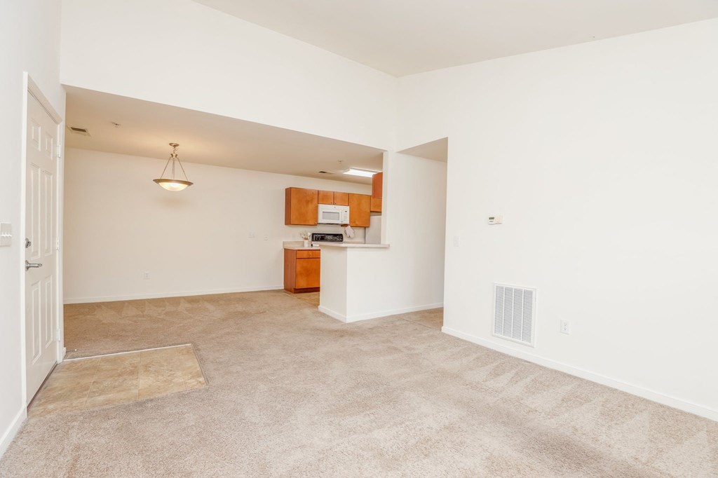 a living room and kitchen with carpeted floors and white walls