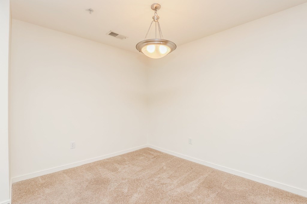 an empty room with white walls and a ceiling light