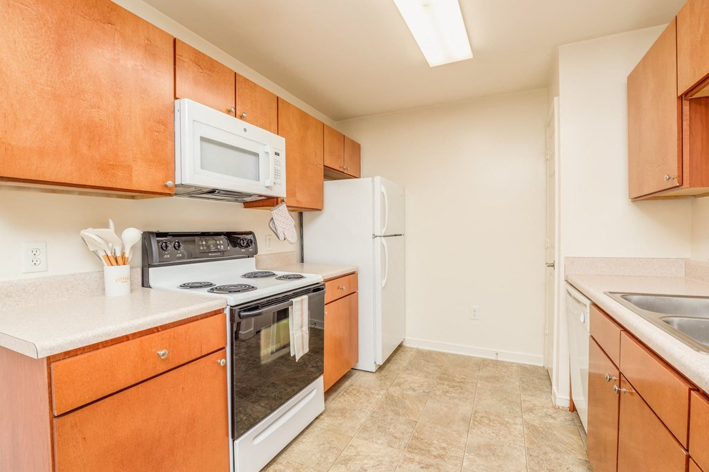 a kitchen with white appliances and wooden cabinets and a white refrigerator