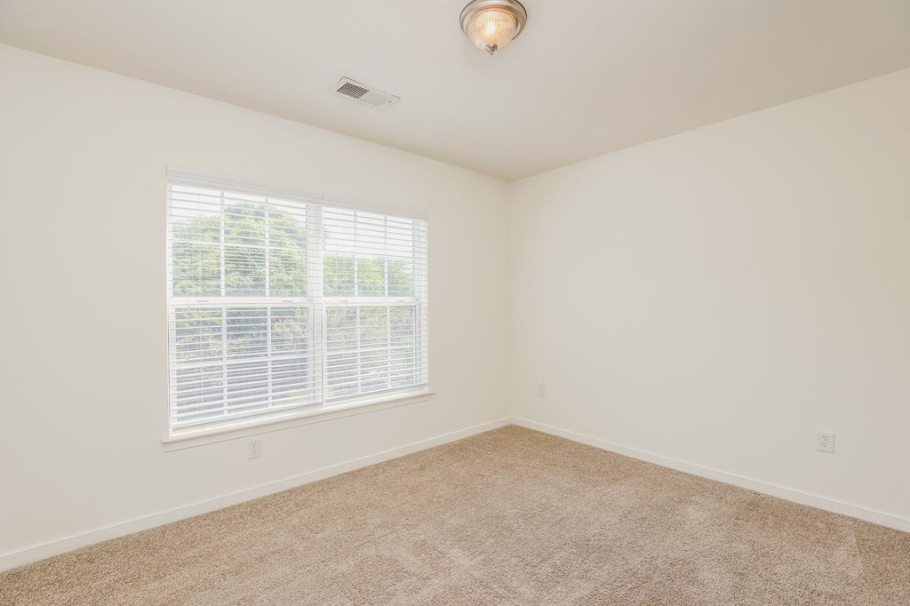 an empty room with a large window and carpet