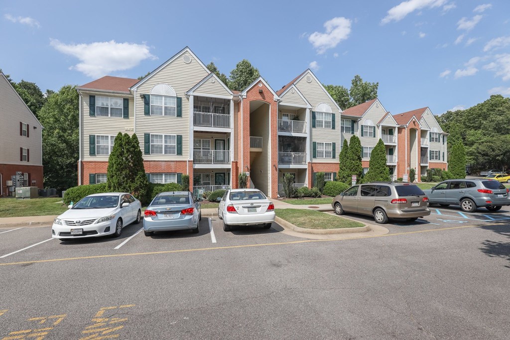 a parking lot with cars in front of an apartment building