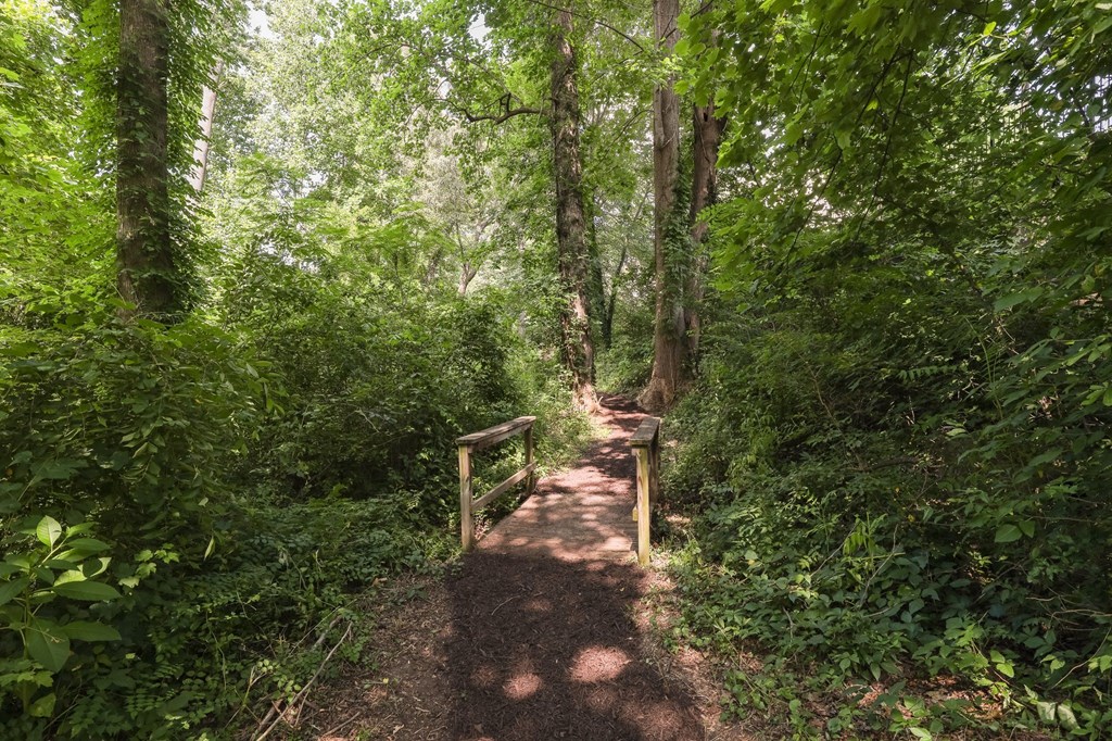 a path through the woods with a fence and a bridge