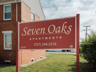 a seven oaks apartments sign in front of a brick building