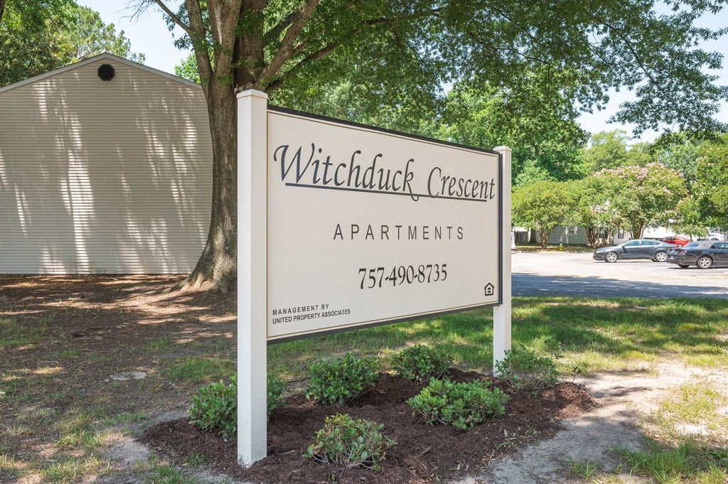 a sign for witchcraft crescent apartments in front of a tree