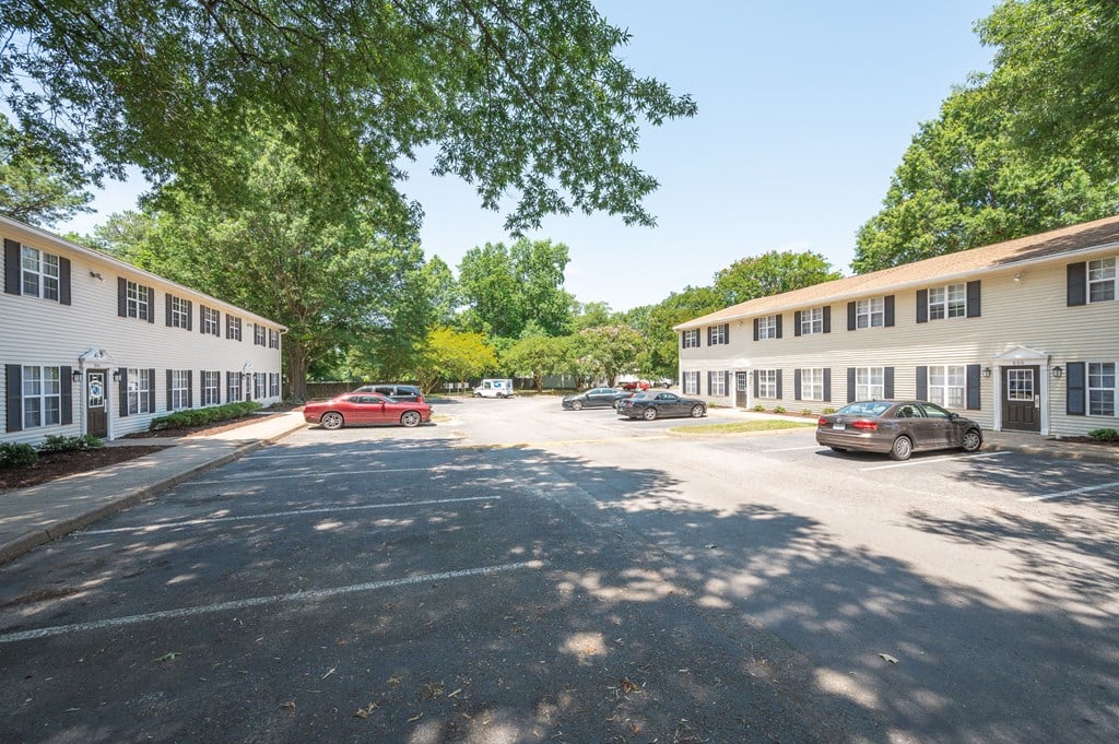 a parking lot with cars in front of several apartment buildings