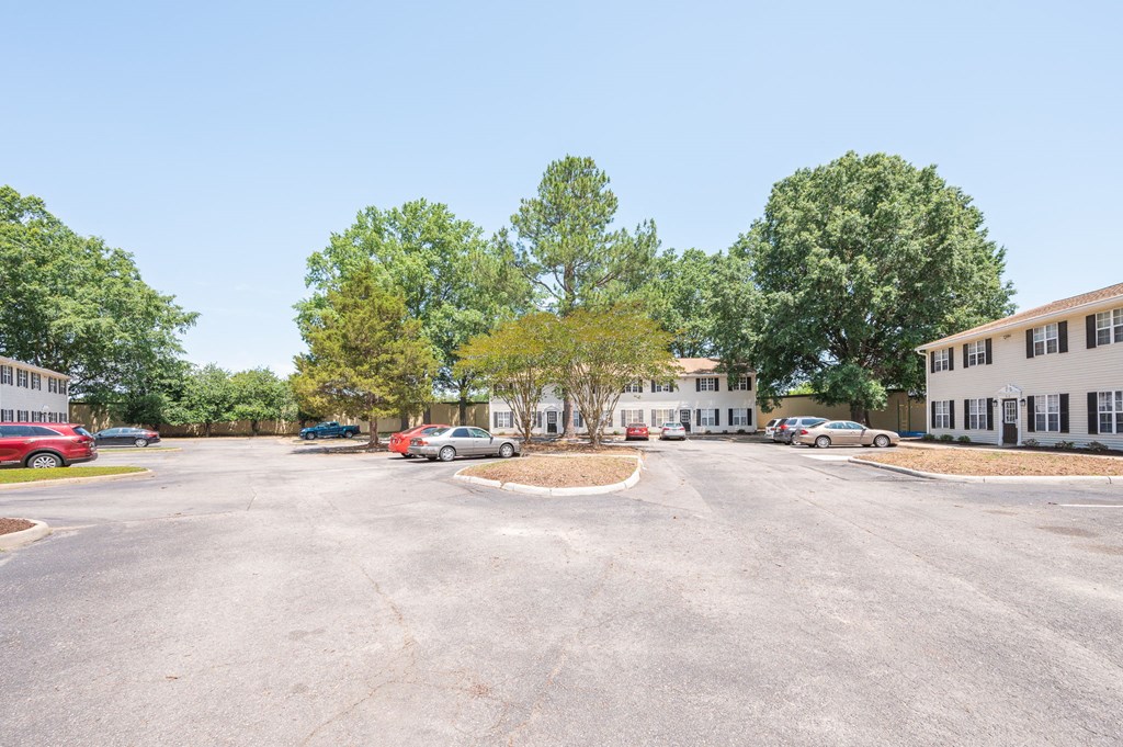 a parking lot with cars parked in front of apartment buildings
