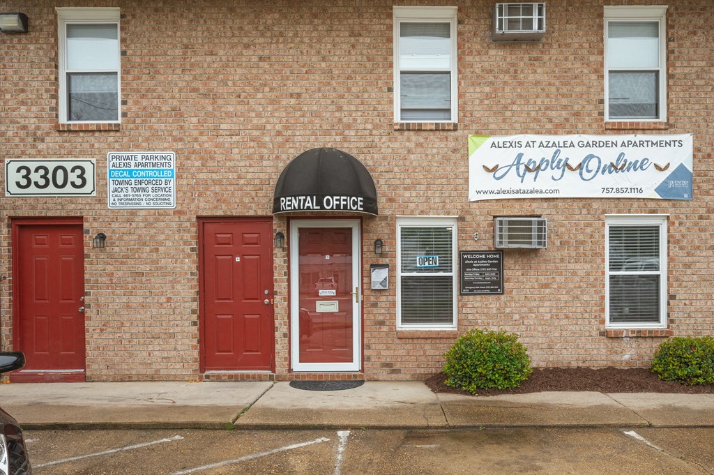 the front of a brick building with two red doors and a sign that reads the