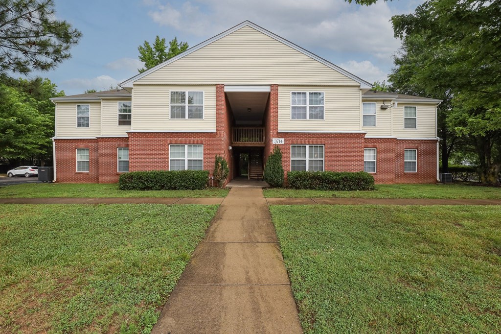 a large brick house with a sidewalk in front of it