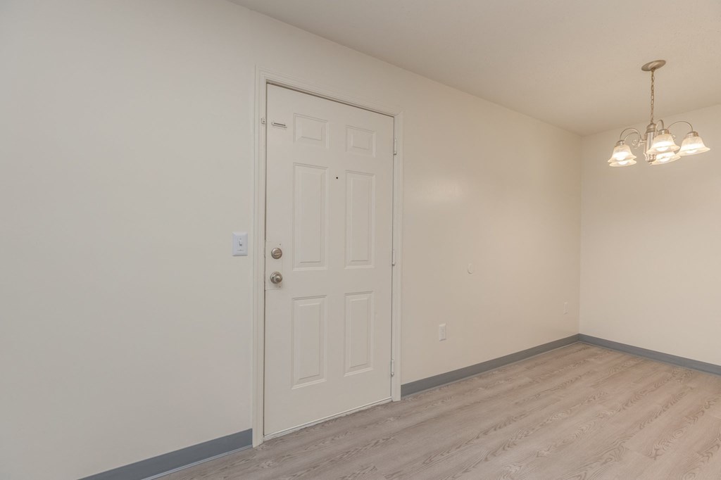 a bedroom with white walls and a white door and a wood floor
