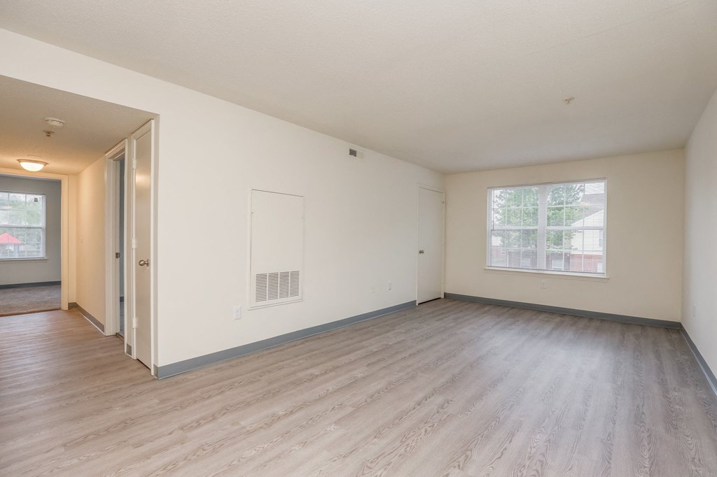 an empty living room with wood floors and a window