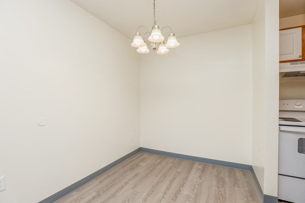 a living room with white walls and wood flooring and a chandelier