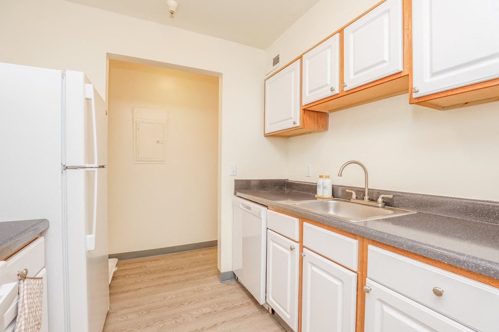 a kitchen with white cabinets and a sink and a refrigerator