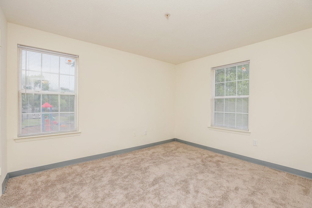 a bedroom with two windows and a carpeted floor