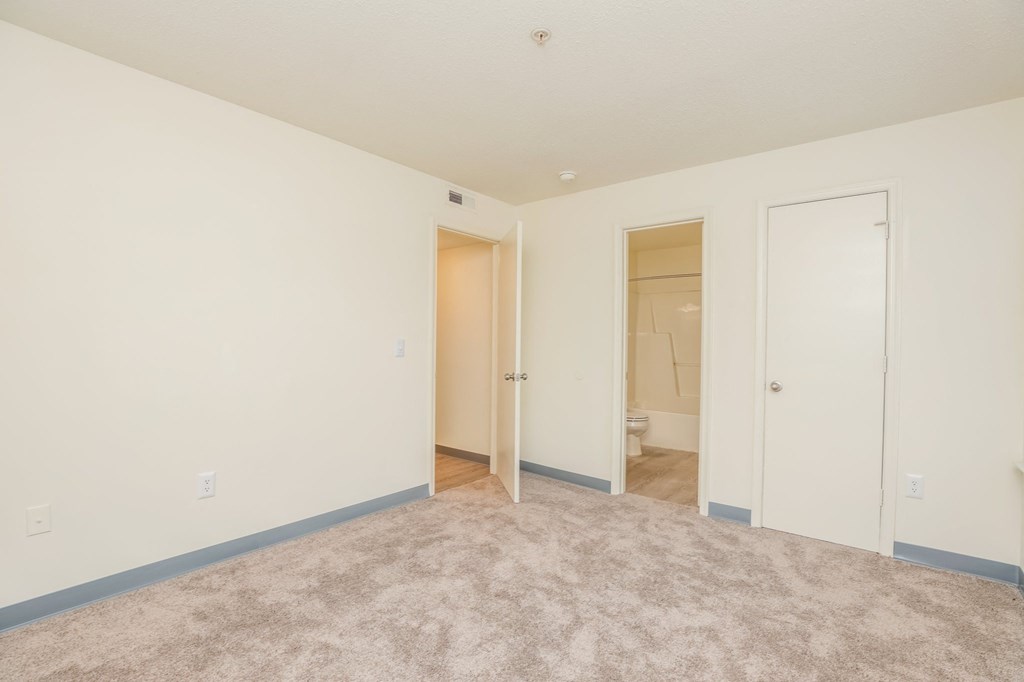 a bedroom with a carpeted floor and a door to a bathroom