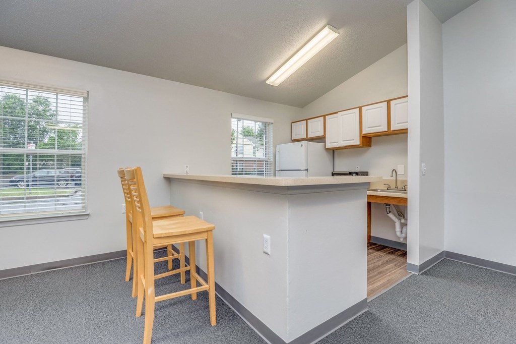 a kitchen with a bar and chairs in front of a window