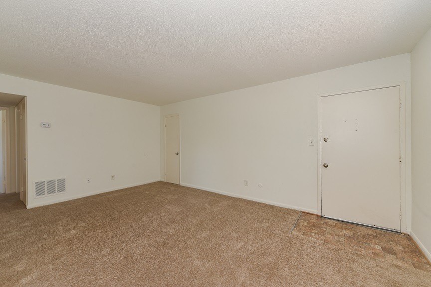 an empty living room with a door to a closet