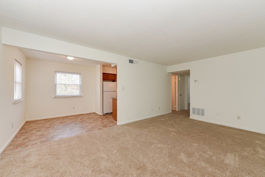the spacious living room and kitchen of an empty house