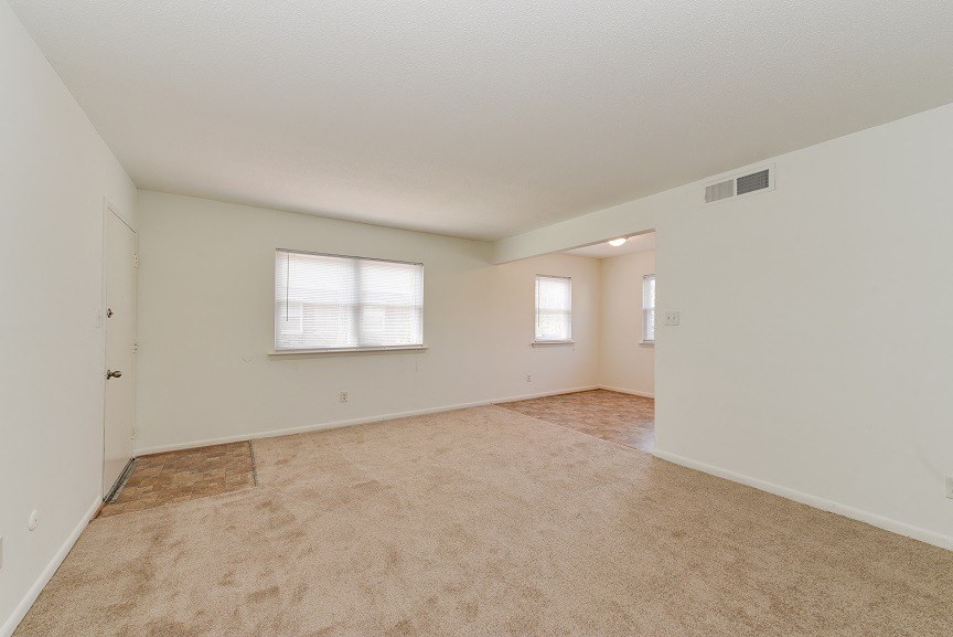 the spacious living room and dining room of an empty house