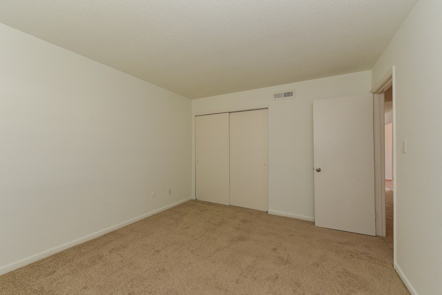 an empty living room with a door to a closet
