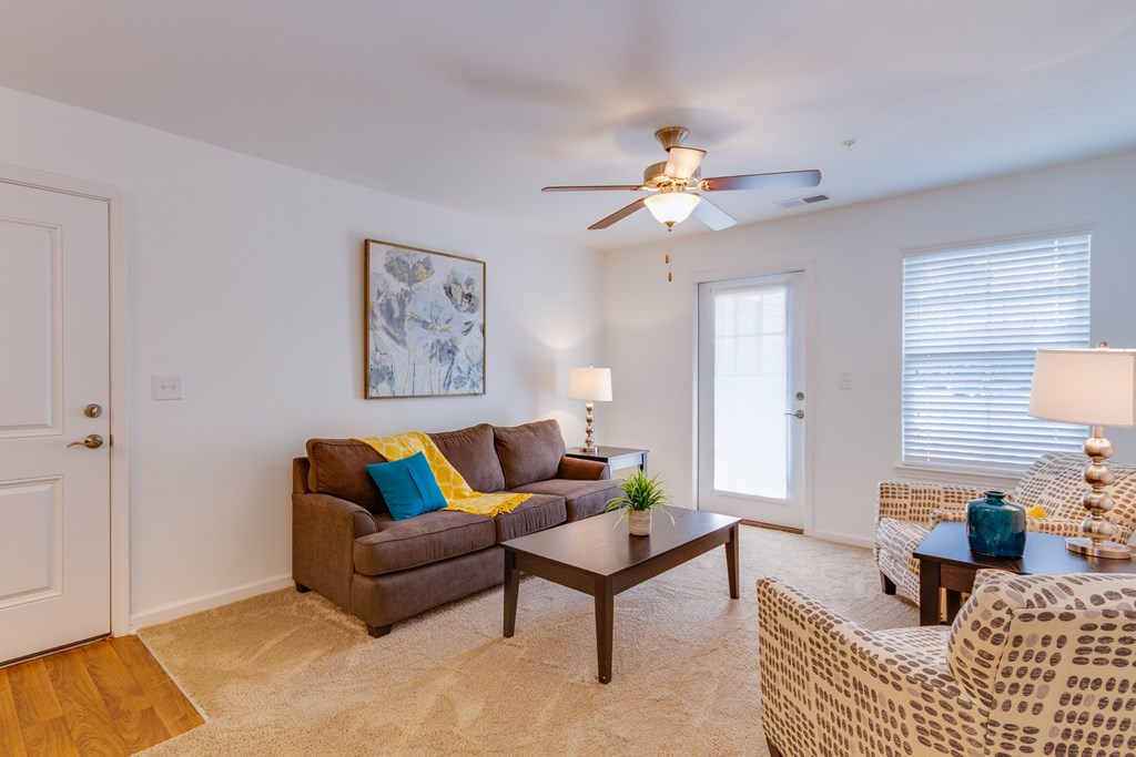 A living room with a brown couch, a coffee table, and a ceiling fan.
