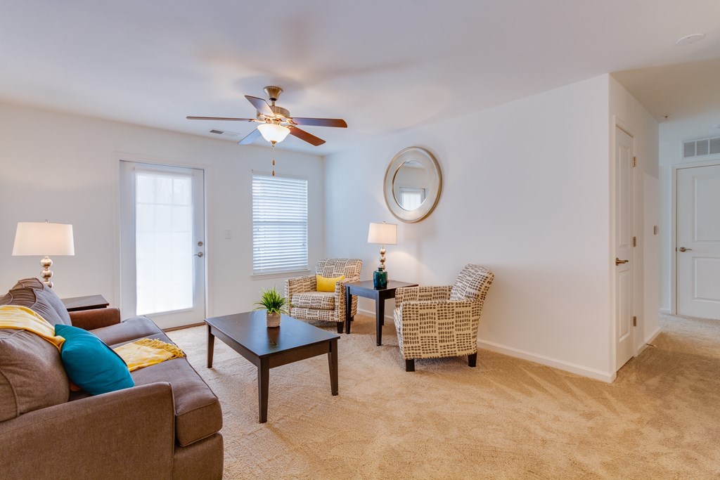 A living room with a brown couch, a coffee table, and a ceiling fan.