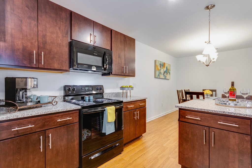 A kitchen with brown cabinets and a black stove top oven.