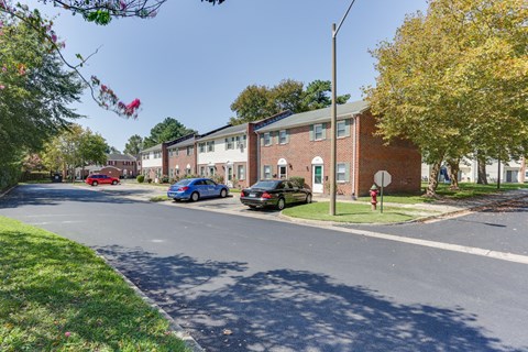 a city street with brick apartment buildings and cars parked on the curb