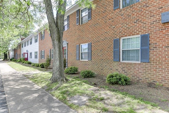 a brick building with blue shuttered windows and a sidewalk
