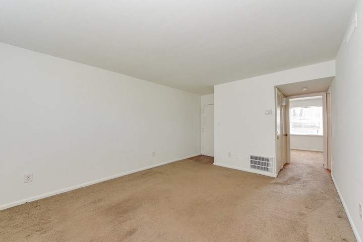 a living room with carpet and a door to a hallway