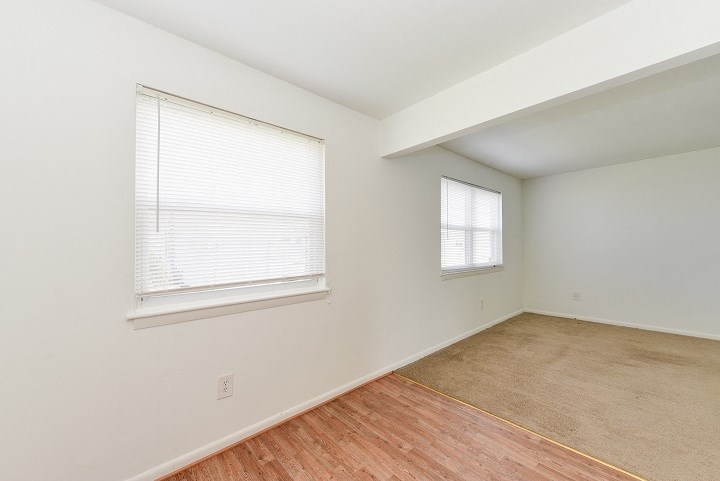 an empty room with a wood floor and two windows