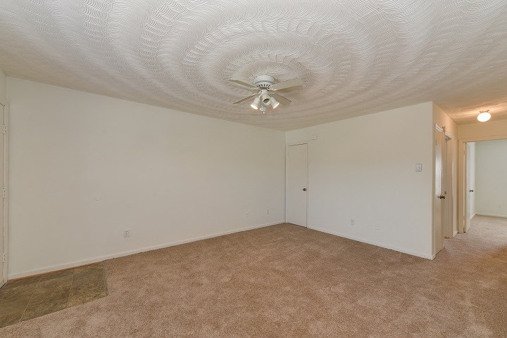 the living room of an empty house with a ceiling fan