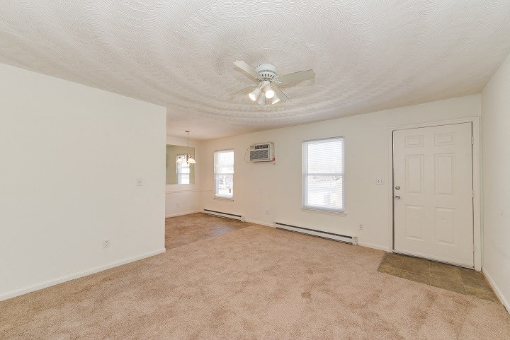 an empty living room with a ceiling fan and a white door