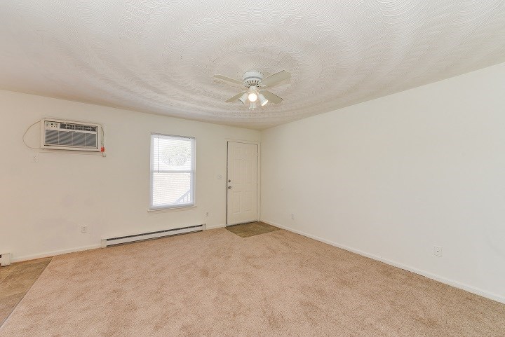 an empty living room with a ceiling fan and a door