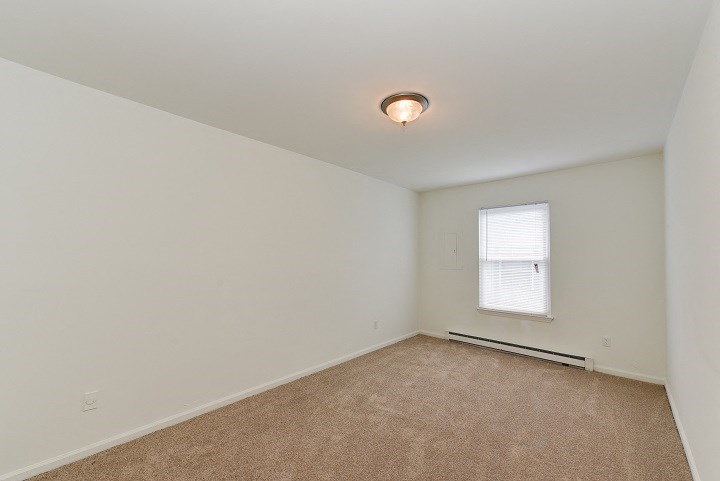 the living room of an empty home with white walls and a window