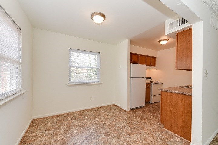 an empty kitchen with a white refrigerator and a window