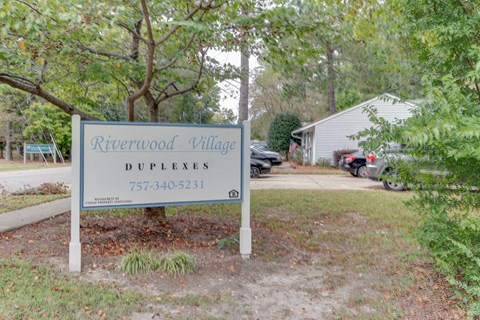 a sign in front of a house with trees
