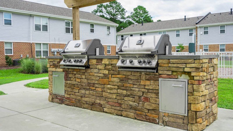 a brick outdoor kitchen with two grills on it
