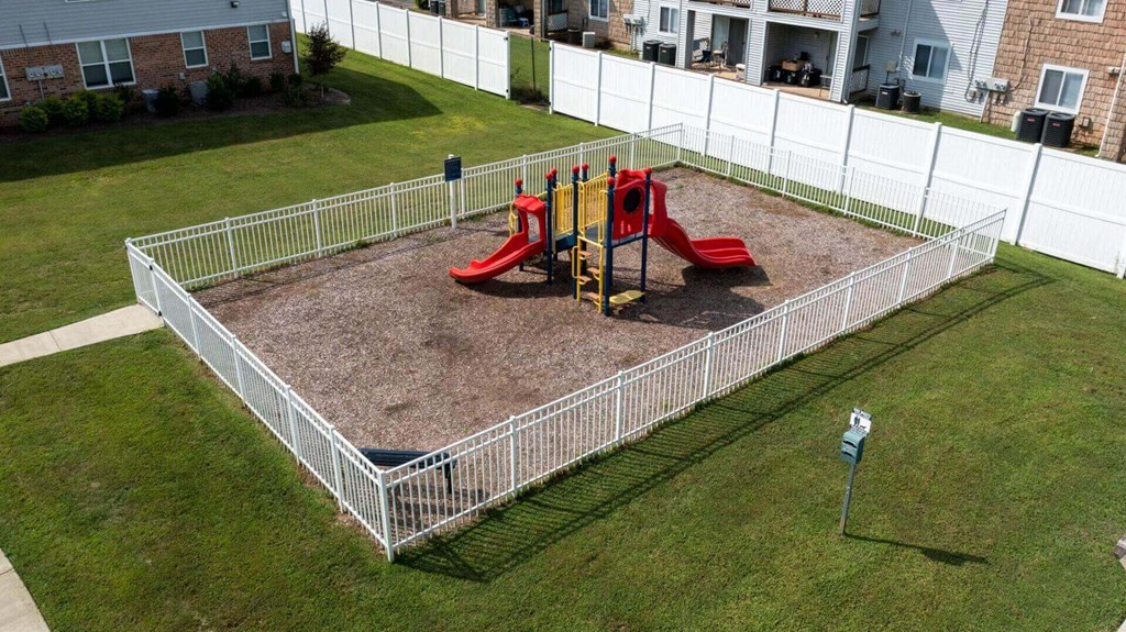 a playground in a yard behind a white fence