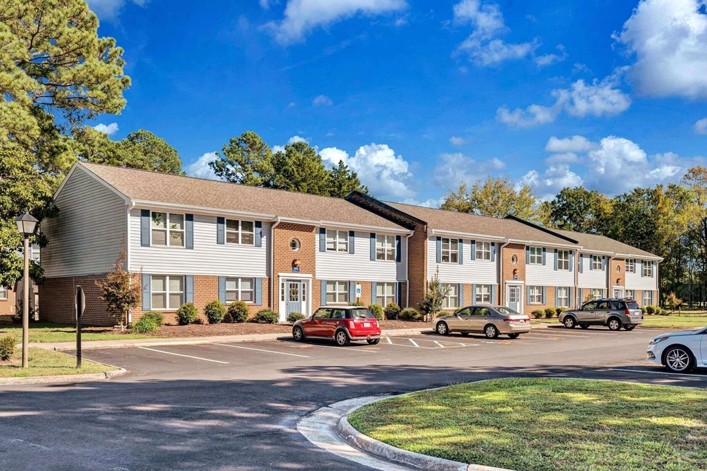 a parking lot with cars parked in front of an apartment building