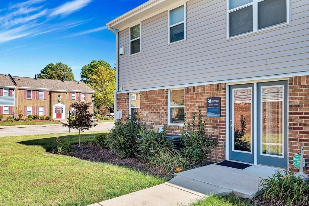 a sidewalk in front of a brick house with a blue door