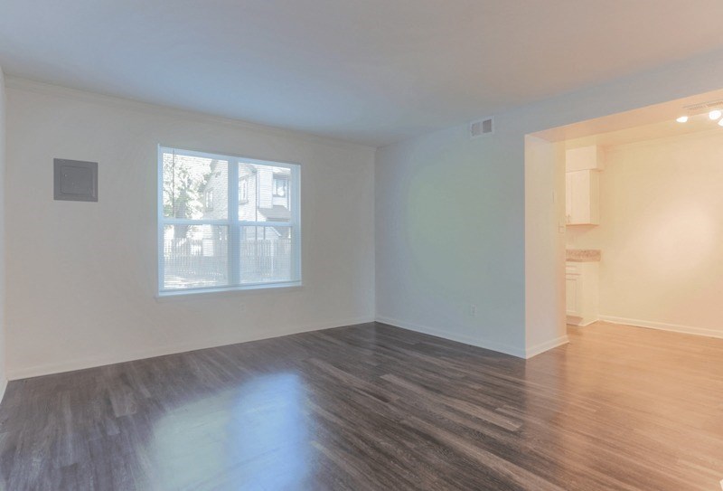 an empty living room with wood floors and a window